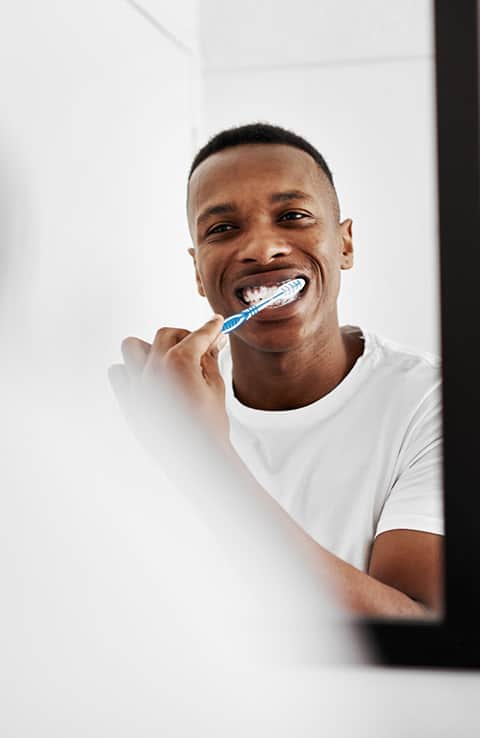 man tandenpoetsen in spiegel met Colgate-tandenborstel man tandenpoetsen in spiegel met Colgate-tandenborstel