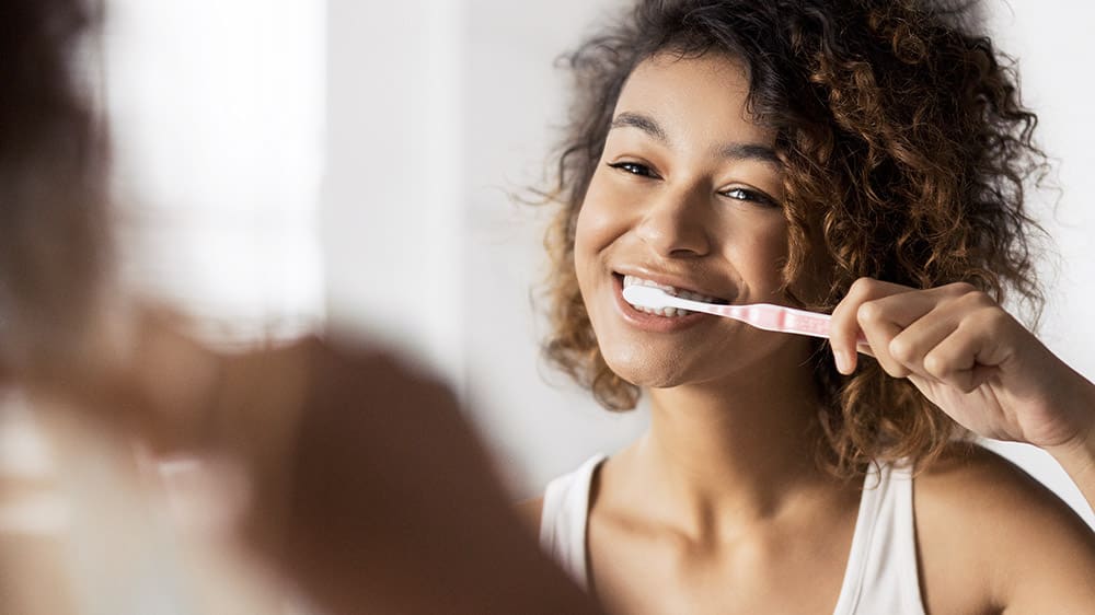 Een jong meisje dat haar tanden poetst met een glimlach voor de spiegel